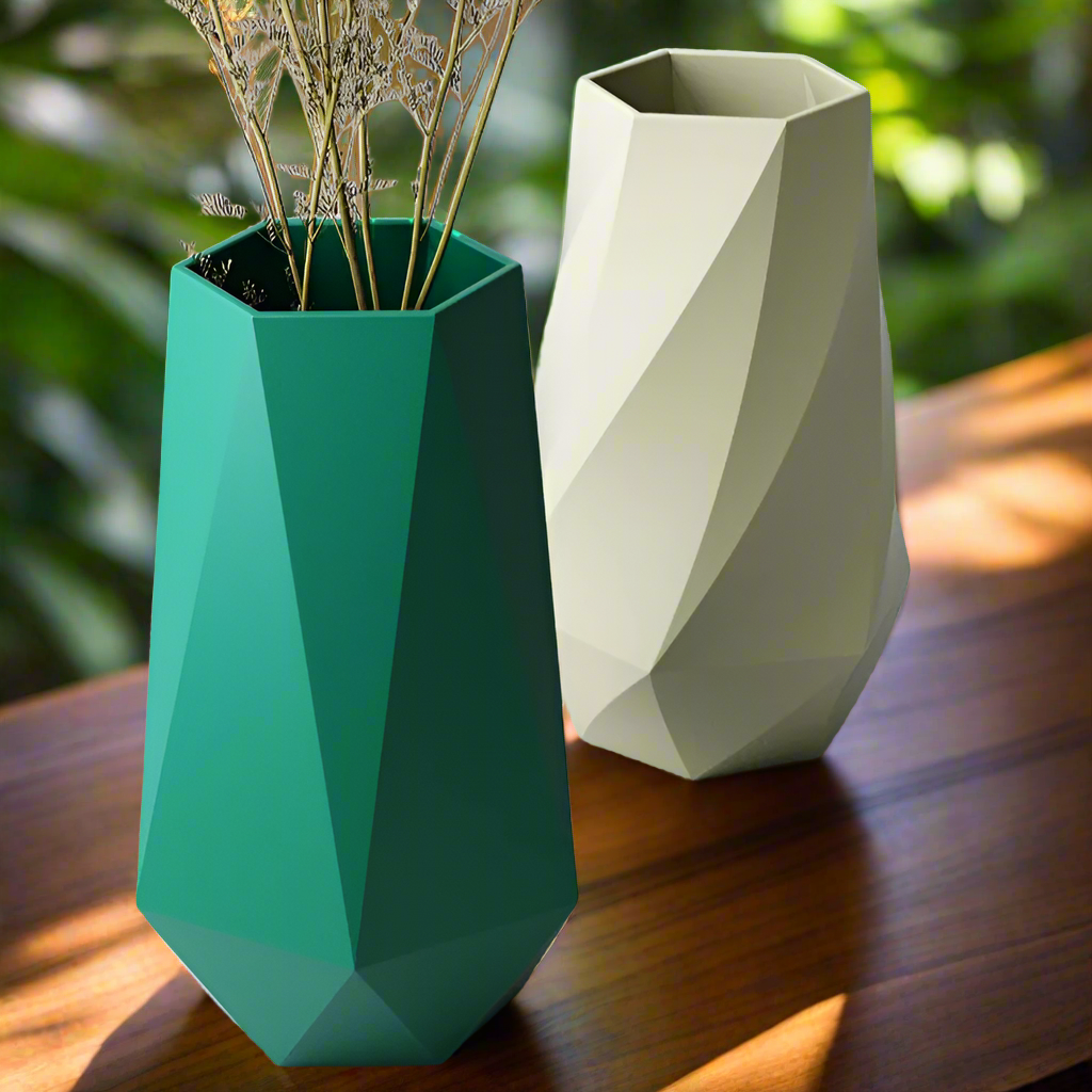 Two geometric vases, one green and one beige, on a wooden surface.